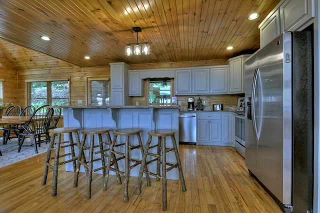 kitchen with a healthy amount of sunlight, light wood-style flooring, wooden ceiling, and stainless steel appliances