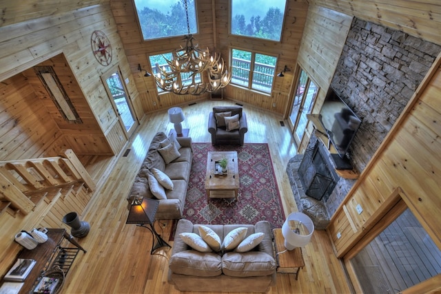 unfurnished living room with a high ceiling, wood walls, a notable chandelier, and wood-type flooring