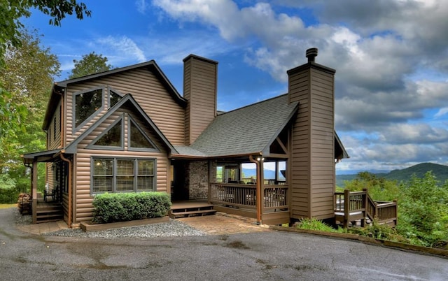 cabin with a chimney, a deck with mountain view, and log veneer siding