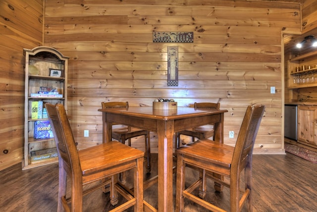 dining area with wooden walls and dark wood finished floors