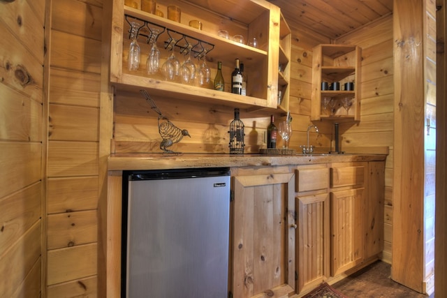bar featuring wooden walls, wet bar, a sink, and refrigerator