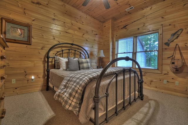 carpeted bedroom featuring a ceiling fan, wood ceiling, wood walls, and visible vents
