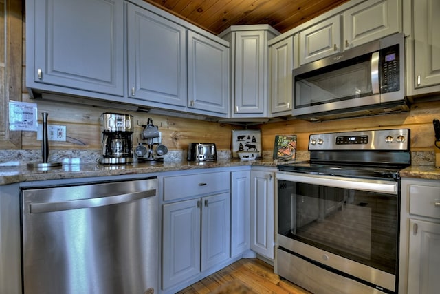 kitchen featuring stone countertops, light wood-style floors, wood ceiling, and stainless steel appliances