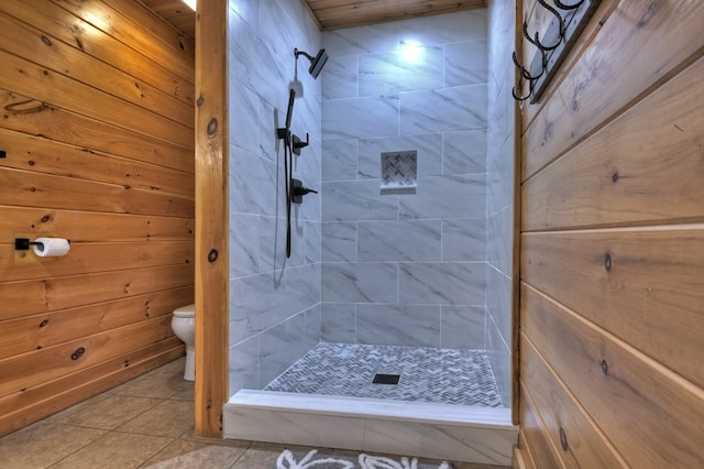 bathroom with toilet, tile patterned flooring, a shower stall, and wood walls