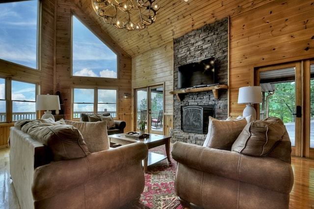 living room featuring a fireplace, wood finished floors, wood walls, and an inviting chandelier