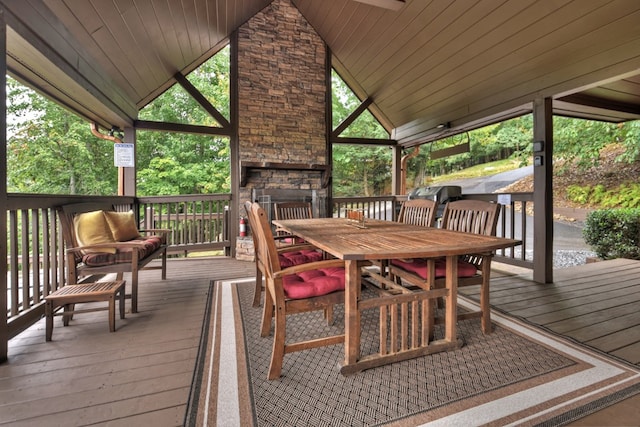wooden deck with an outdoor stone fireplace and outdoor dining space