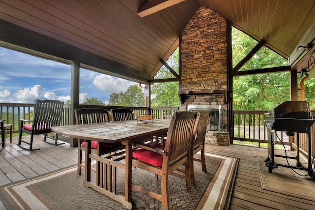 wooden deck featuring outdoor dining space, area for grilling, and a stone fireplace