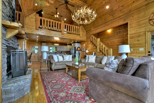 living room featuring high vaulted ceiling, wood ceiling, stairway, wooden walls, and light wood-style flooring