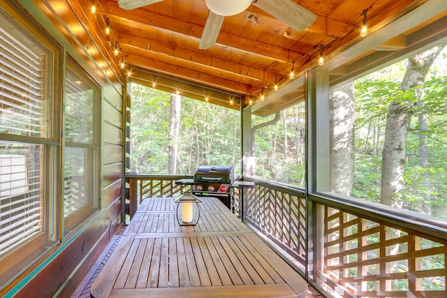 unfurnished sunroom with lofted ceiling with beams, ceiling fan, and wooden ceiling