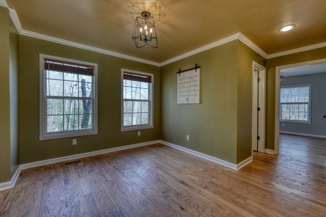 spare room featuring baseboards, crown molding, visible vents, and wood finished floors