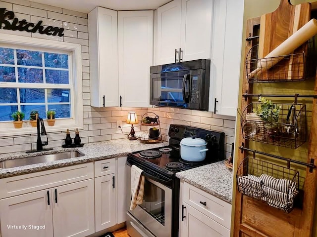 kitchen with electric stove, black microwave, a sink, and tasteful backsplash