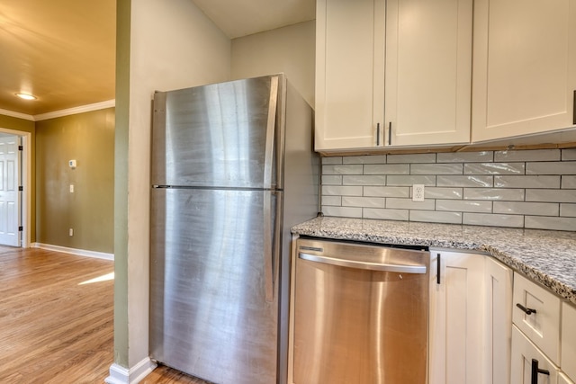 kitchen with light stone counters, crown molding, stainless steel appliances, tasteful backsplash, and light wood-type flooring