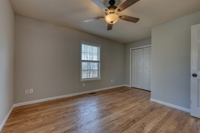 unfurnished bedroom featuring baseboards, visible vents, a ceiling fan, light wood-style floors, and a closet