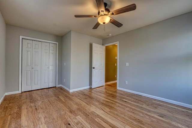 unfurnished bedroom with a closet, ceiling fan, light wood-style flooring, and baseboards