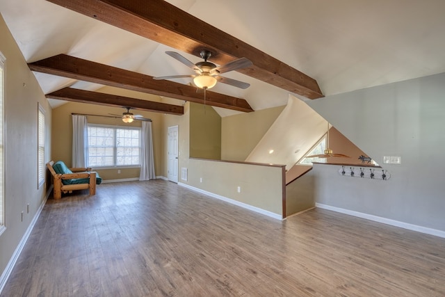 interior space featuring an upstairs landing, lofted ceiling with beams, baseboards, and wood finished floors