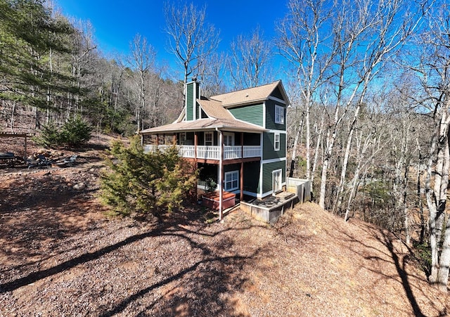 rear view of house with a balcony and a chimney