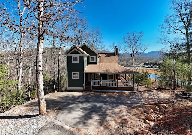 view of front of property featuring a porch, a chimney, a mountain view, and aphalt driveway