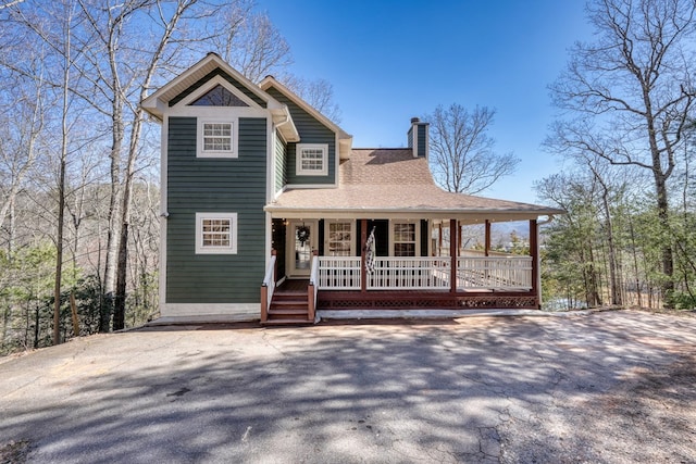 view of front of home featuring covered porch, a chimney, and roof with shingles