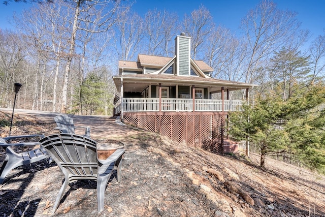 back of property with covered porch and a chimney