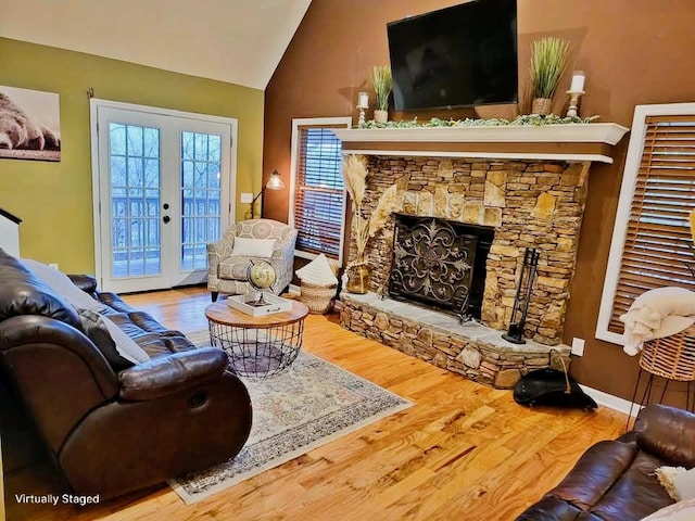 living room featuring vaulted ceiling, french doors, a fireplace, and wood finished floors