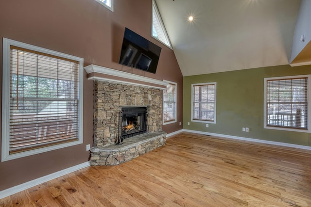 unfurnished living room with high vaulted ceiling, a fireplace, wood finished floors, and baseboards