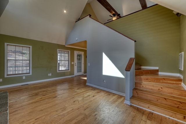 interior space featuring high vaulted ceiling, stairway, baseboards, and wood finished floors