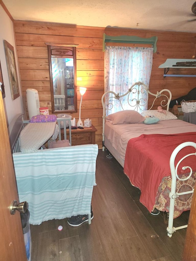 bedroom with dark hardwood / wood-style floors and wood walls