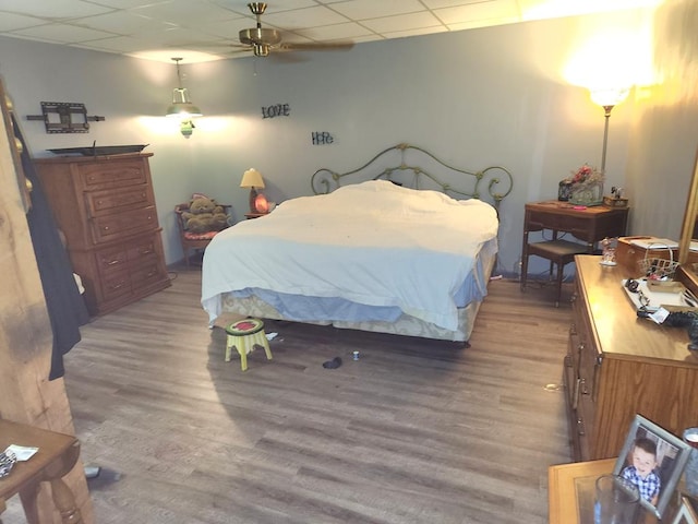 bedroom featuring wood-type flooring and a drop ceiling