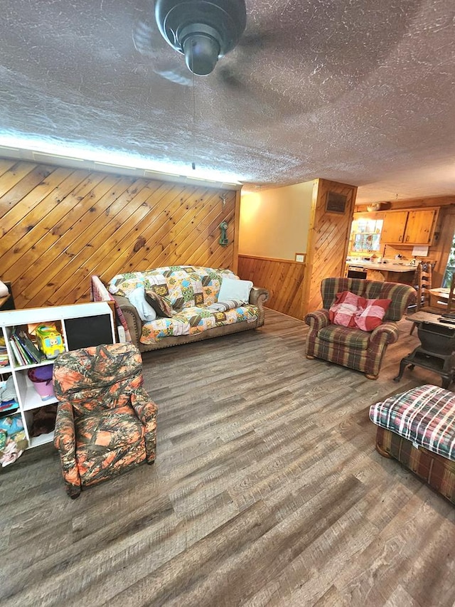 living room featuring hardwood / wood-style flooring, wooden walls, and a textured ceiling