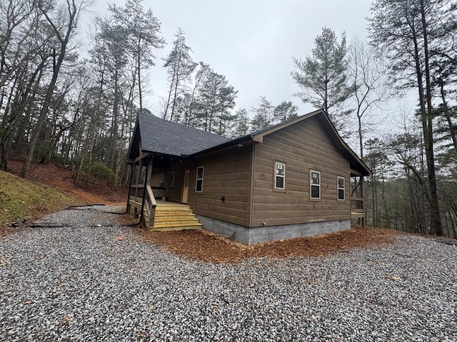 view of side of property with driveway and a shingled roof