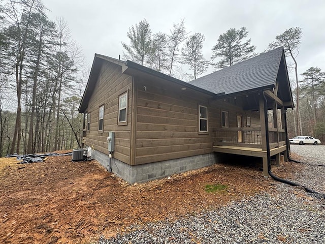 view of home's exterior featuring central AC unit and roof with shingles