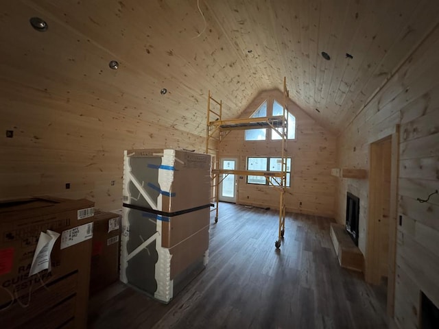 bonus room with wooden walls, a fireplace with raised hearth, wooden ceiling, dark wood-type flooring, and high vaulted ceiling