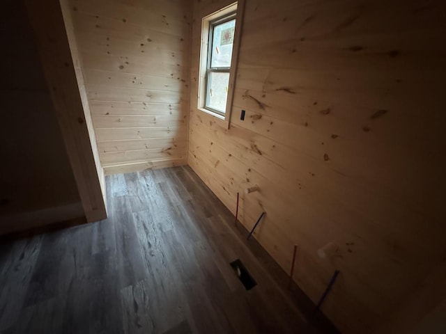 spare room with dark wood-type flooring and wood walls