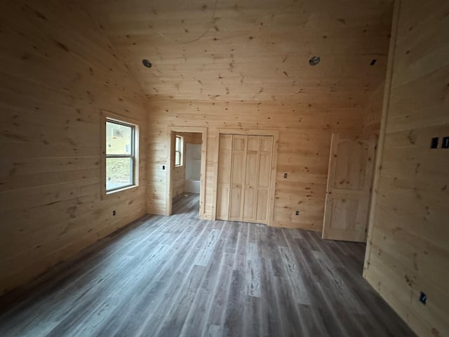 unfurnished bedroom featuring wood walls, high vaulted ceiling, and dark wood-style flooring