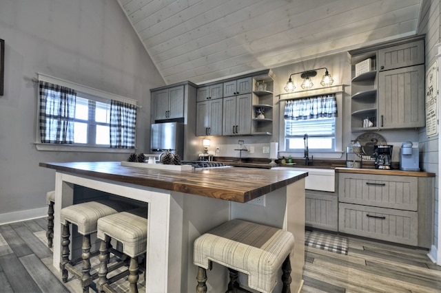 kitchen with a sink, a healthy amount of sunlight, open shelves, and butcher block counters