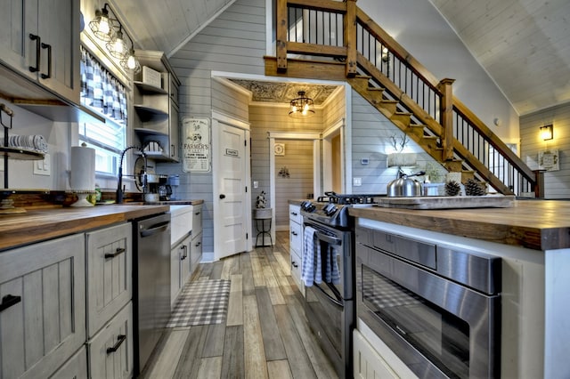 kitchen with butcher block countertops, light wood finished floors, open shelves, and stainless steel appliances