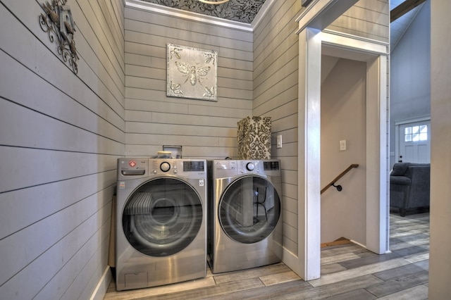 laundry room featuring wooden walls, independent washer and dryer, laundry area, and wood finished floors