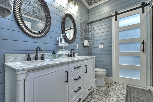 bathroom featuring wood walls, double vanity, a sink, and toilet