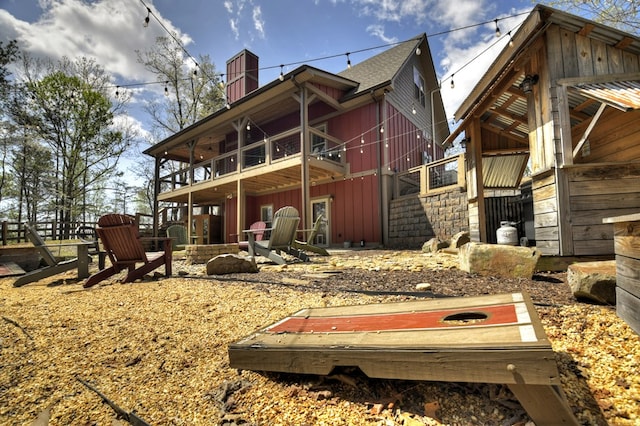 back of house featuring roof with shingles, board and batten siding, and a chimney