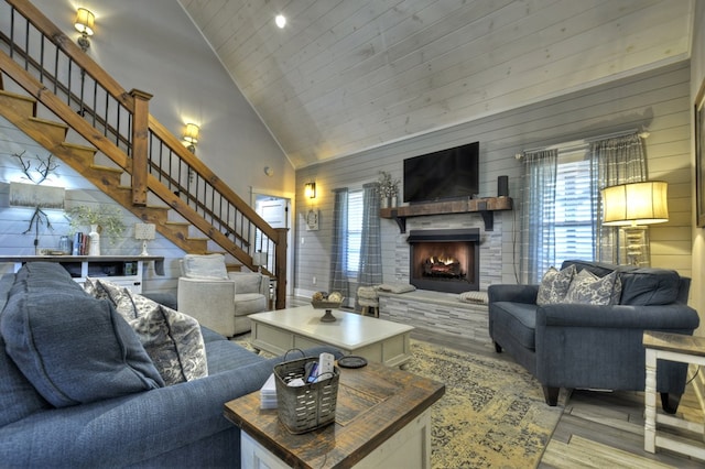 living room featuring a stone fireplace, wood ceiling, stairway, wood finished floors, and high vaulted ceiling