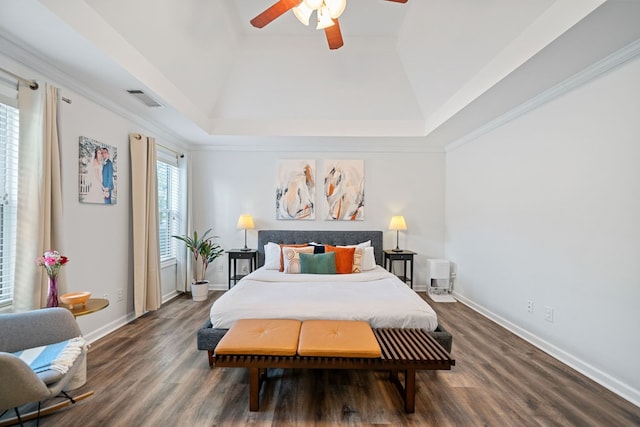 bedroom featuring baseboards, visible vents, a ceiling fan, dark wood-style flooring, and a tray ceiling