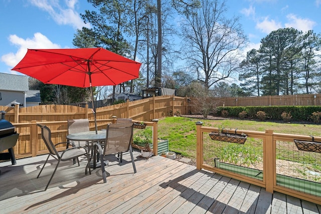 wooden terrace featuring outdoor dining area, a fenced backyard, and a yard