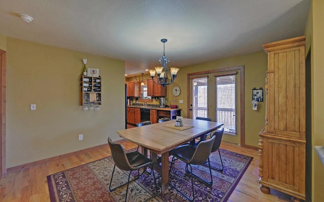 dining room with a chandelier, light wood finished floors, and baseboards