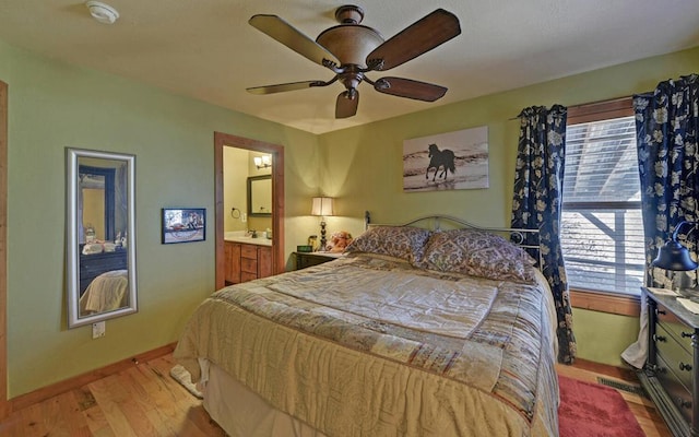 bedroom with ensuite bathroom, a ceiling fan, visible vents, baseboards, and light wood finished floors