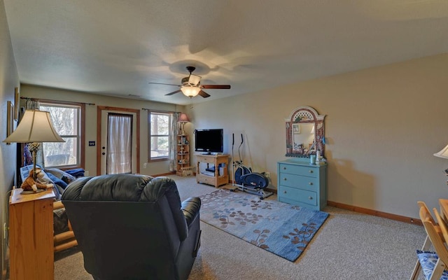 living area with baseboards, a ceiling fan, and light colored carpet