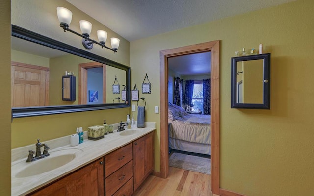 bathroom with a sink, double vanity, connected bathroom, and wood finished floors