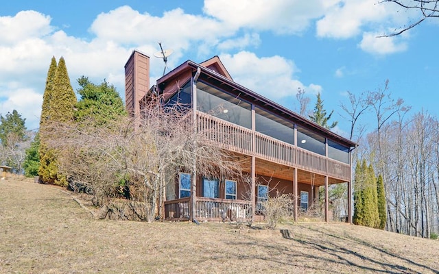 rear view of house with a deck, a yard, and a chimney