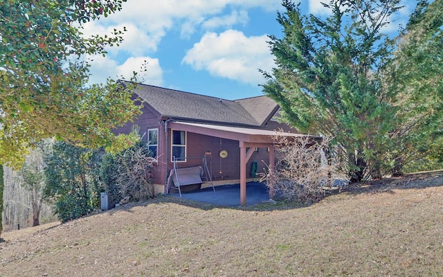 back of property featuring a shingled roof and a yard