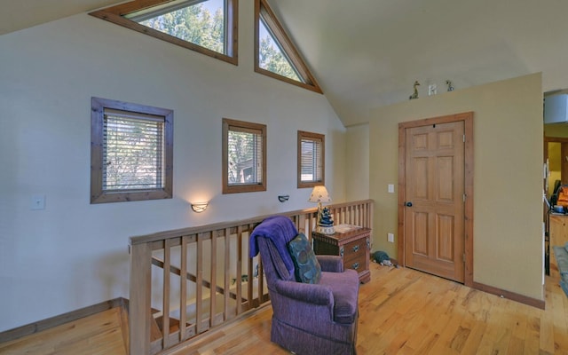 living area featuring high vaulted ceiling, light wood finished floors, and baseboards