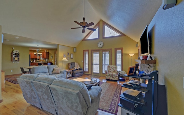 living room with light wood-type flooring, high vaulted ceiling, and ceiling fan with notable chandelier